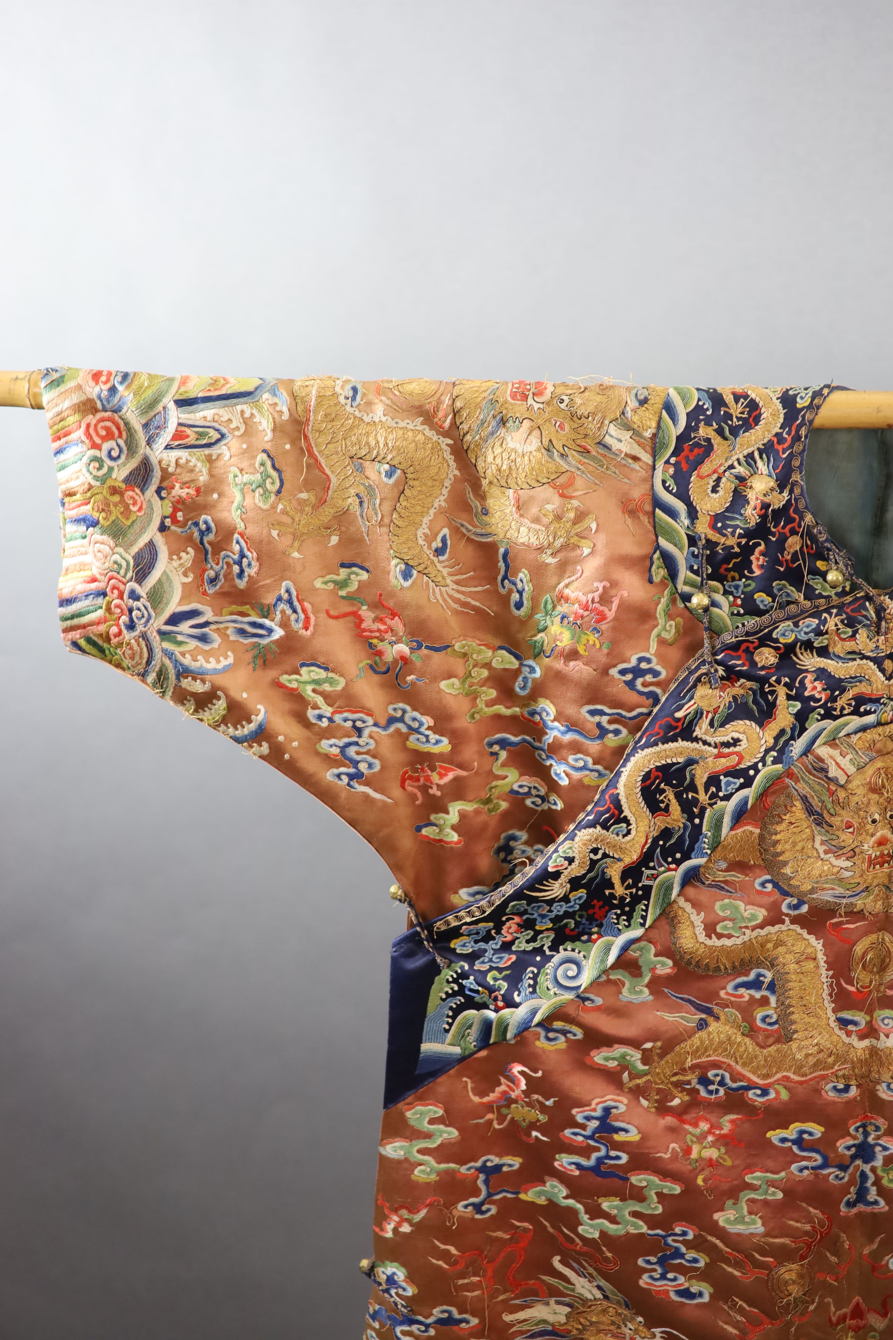 A Chinese apricot embroidered silk ‘dragon’ formal court robe, jifu, late Qing Dynasty, 131cm long, some alterations